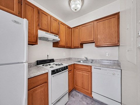 A kitchen with white appliances and wooden cabinets.