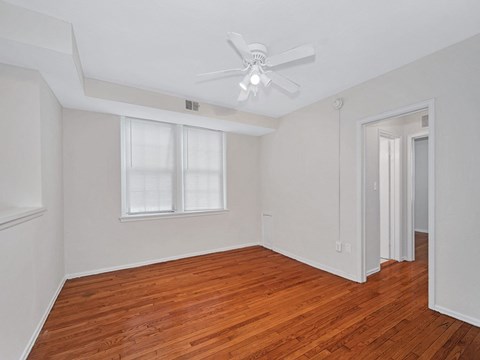A room with a ceiling fan and wooden floors.