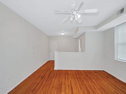 A room with a ceiling fan and wooden flooring.