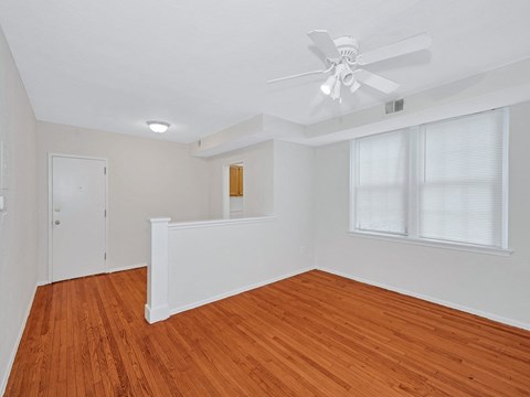A room with a ceiling fan and wooden floors.