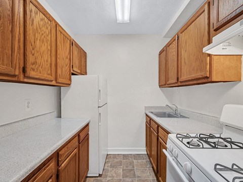 A kitchen with white appliances and wooden cabinets.