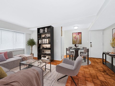 A living room with a grey couch, a glass coffee table, and a bookshelf.