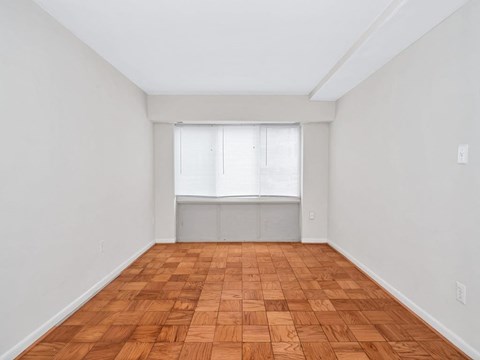 A room with wooden flooring and a window with blinds.