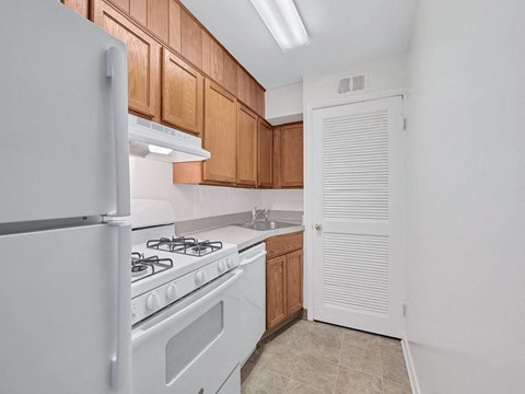 A kitchen with a white refrigerator, white stove, and brown cabinets.