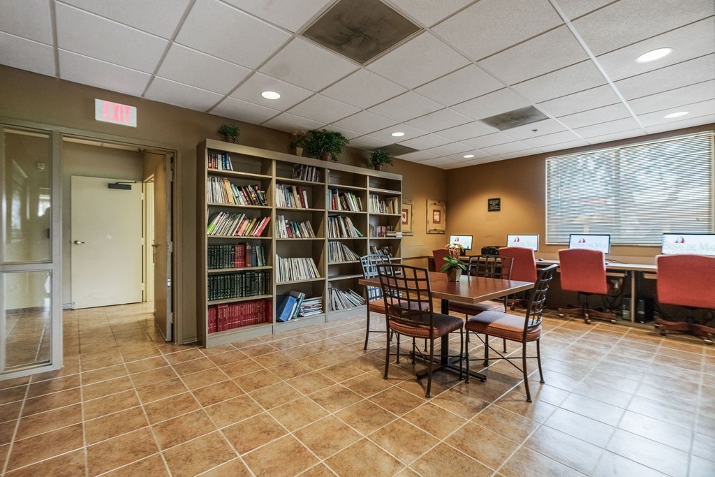 a library with a table and chairs and a book shelf