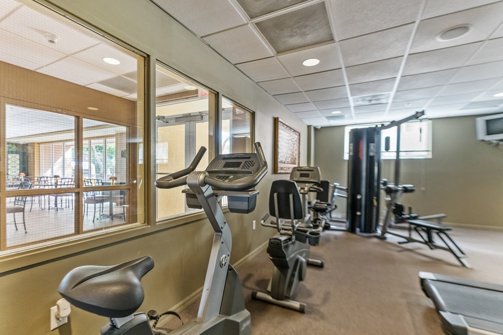 a gym with exercise machines and chairs in the lobby of a building