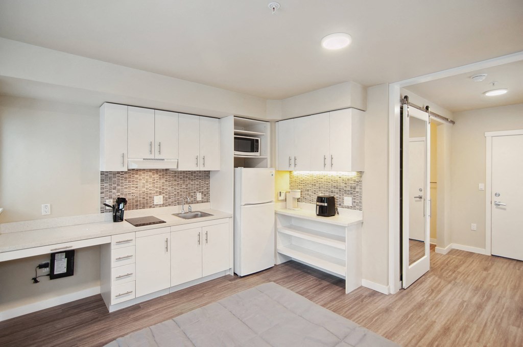 A kitchen with white cabinets and a wooden floor.