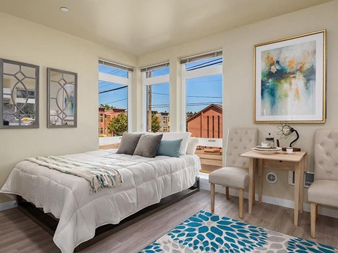 a bedroom with a bed and a desk and windows