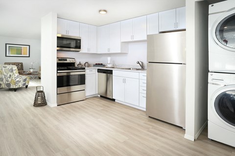 a kitchen with white cabinets and stainless steel appliances and a washer and dryer