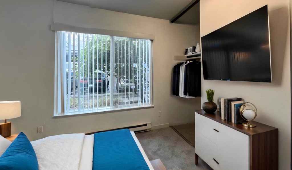 a bedroom with a bed and a large window and a tv