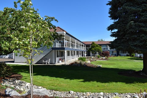 a large white building with a red roof and a lawn in front of it