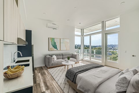 A cozy bedroom with a comfortable bed, couch, and large window offering natural light and scenic views.