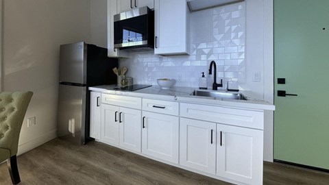 a kitchen with white cabinets and a sink and a refrigerator