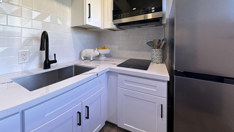 a kitchen with white cabinets and a sink and a refrigerator