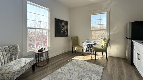 a living room and dining room with a table and two windows