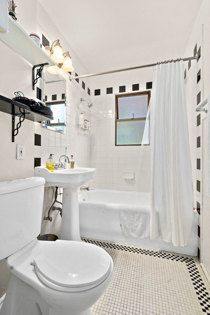 a black and white bathroom with a toilet sink and tub