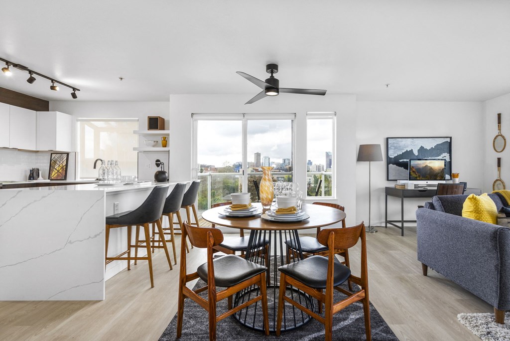 a dining area with a round dining table and four chairs and a kitchen with a breakfast bar