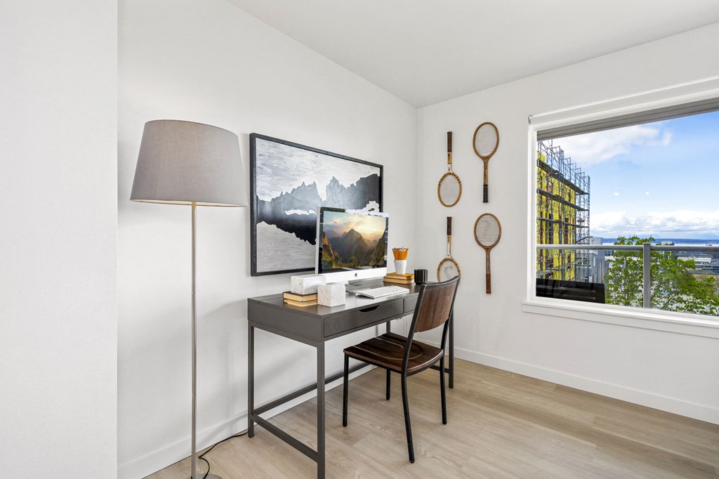 a desk with a chair and a lamp in a room with a large window