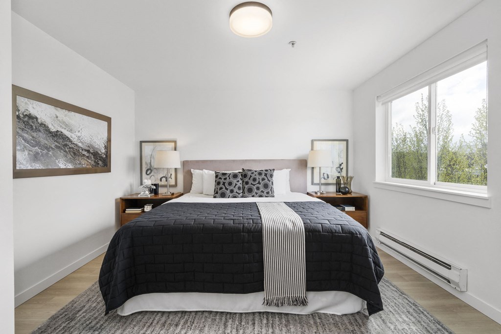 a bedroom with a large bed and two windows