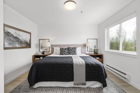 a bedroom with a large bed and two windows