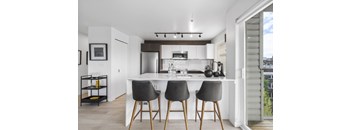 a kitchen with white cabinetry and a large island with three stools in front of it