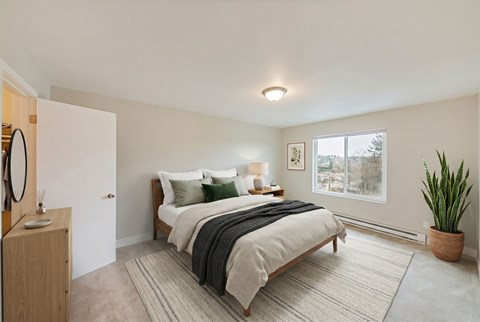 A bedroom with a large bed and a potted plant.