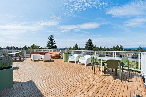 A wooden deck with white chairs and green planters.