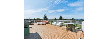 A wooden deck with white chairs and green planters.