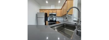 A kitchen with a sink, refrigerator, and microwave.