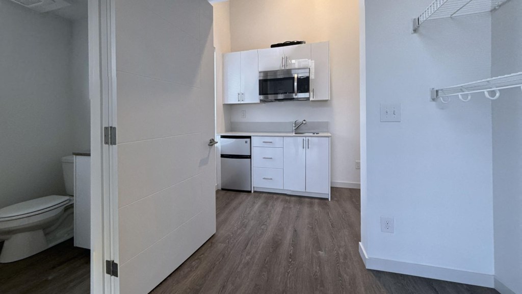 an empty room with a kitchen and a toilet