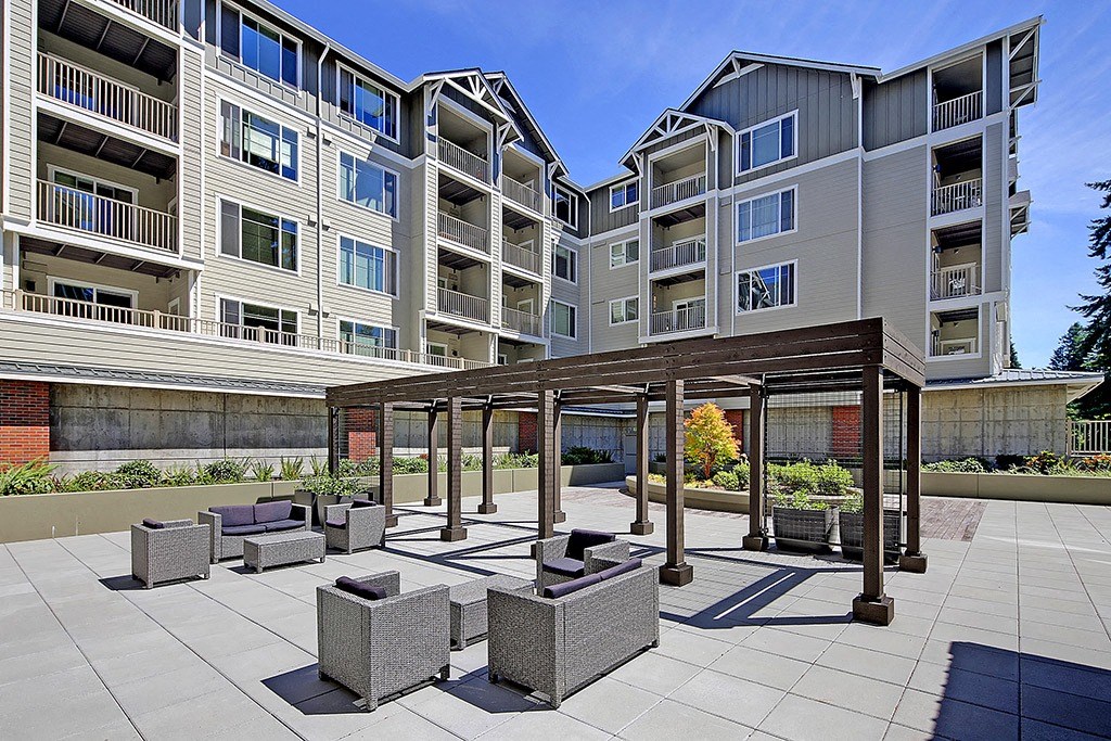 an outdoor patio area with stone furniture in front of an apartment building