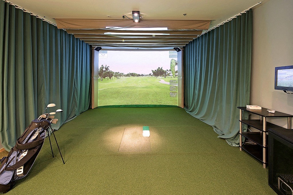 a room with green carpet and curtains and a view of a golf course