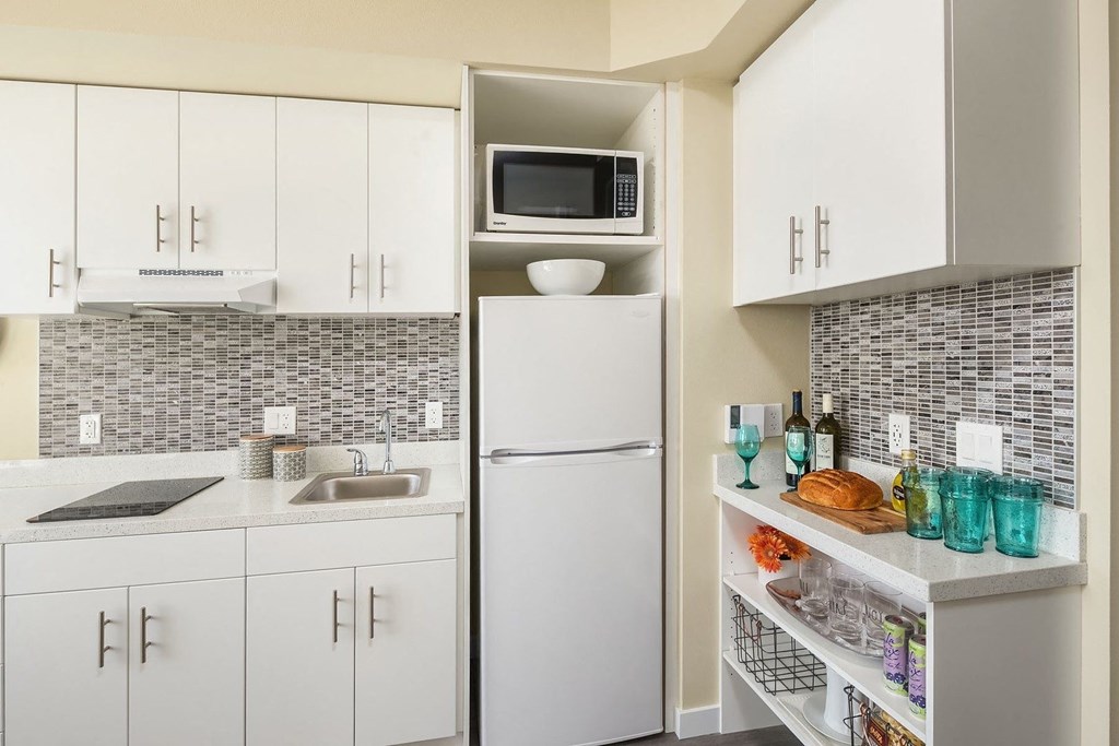 A kitchen with white cabinets and a white refrigerator.