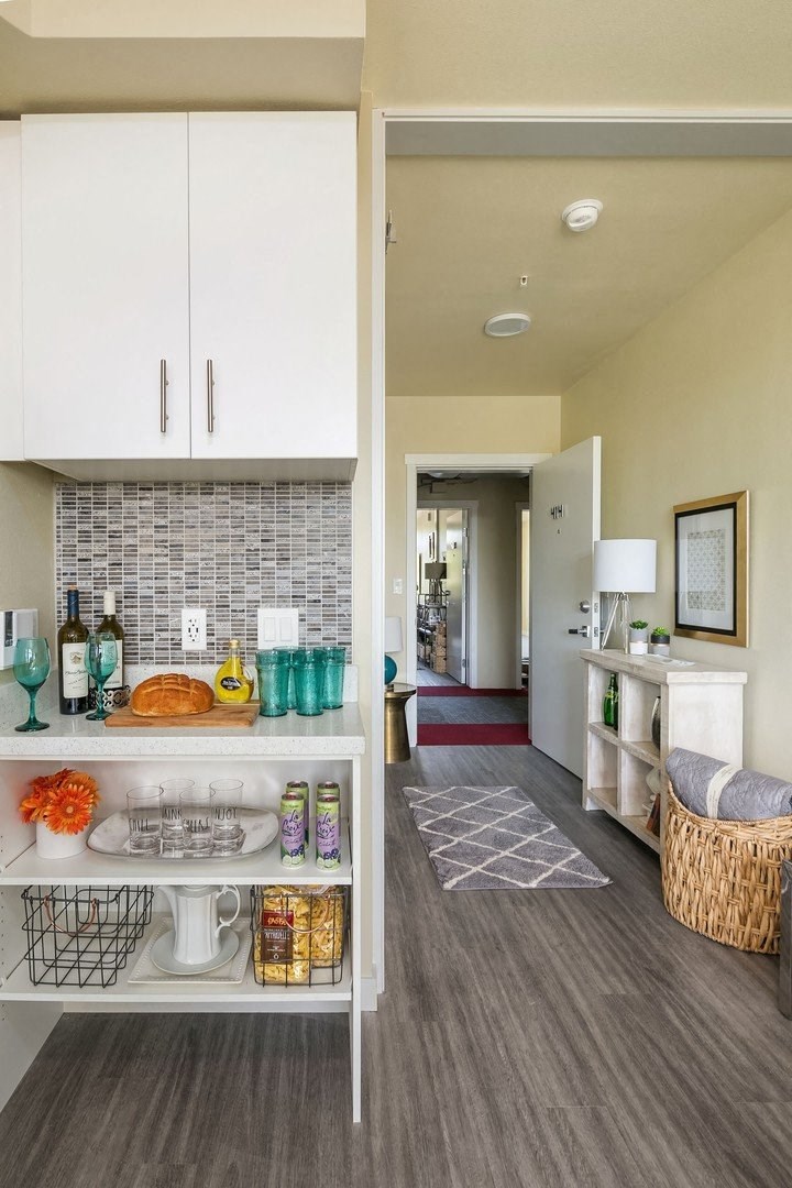 A kitchen with white cabinets and a grey floor.