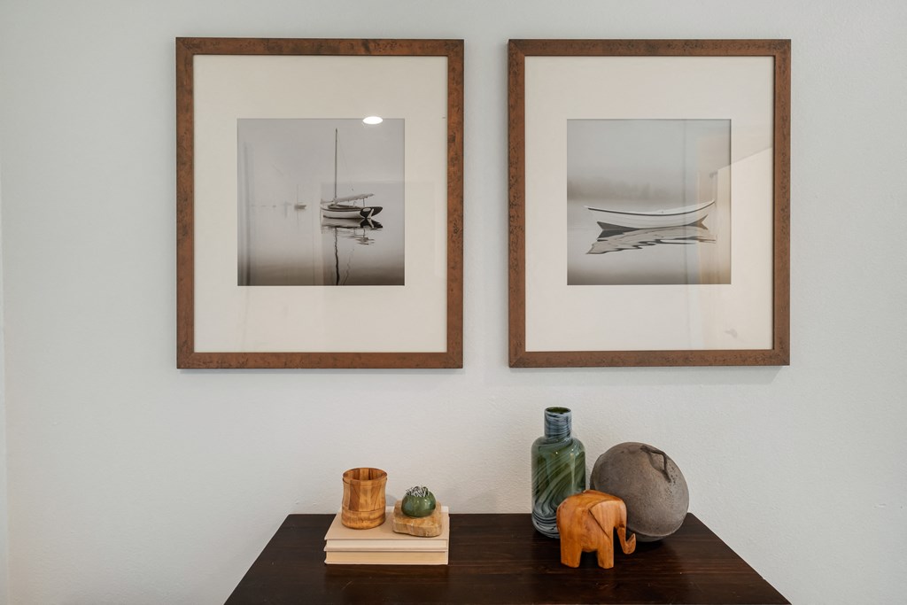 a wall with two framed pictures and a wooden table with various objects on it