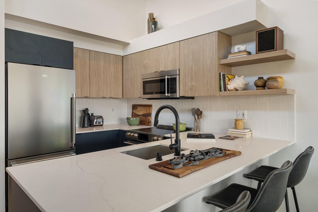 a kitchen with a white counter top and a stainless steel refrigerator