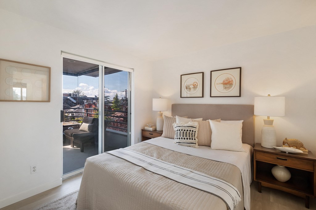 a bedroom with a large bed and a sliding glass door leading to a balcony