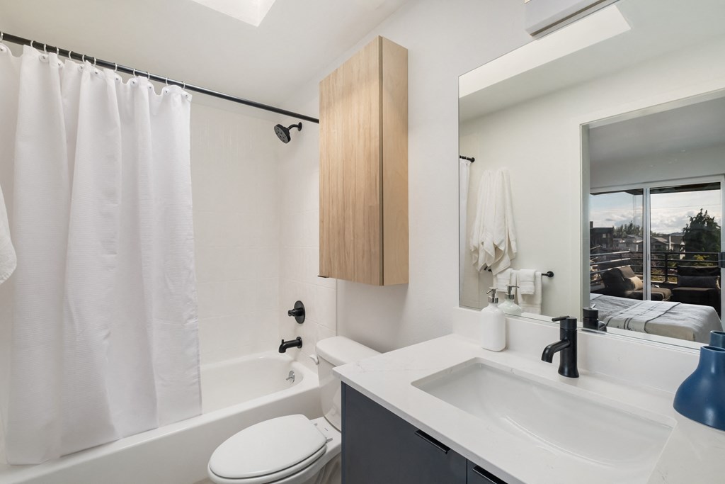 a bathroom with a white sink and toilet next to a bathtub with a shower curtain