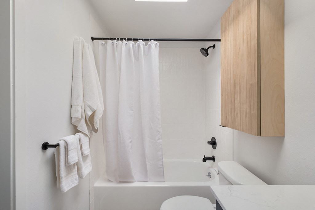 a bathroom with white walls and a white bathtub with a white shower curtain