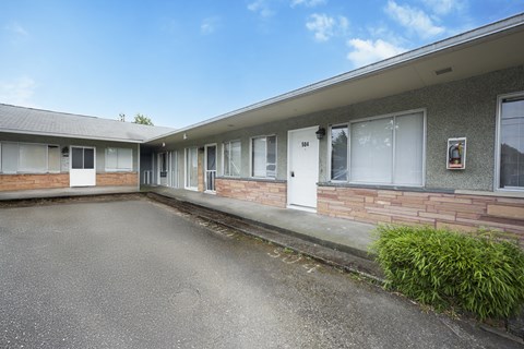 A building with a white door and windows with a grey sky in the background.