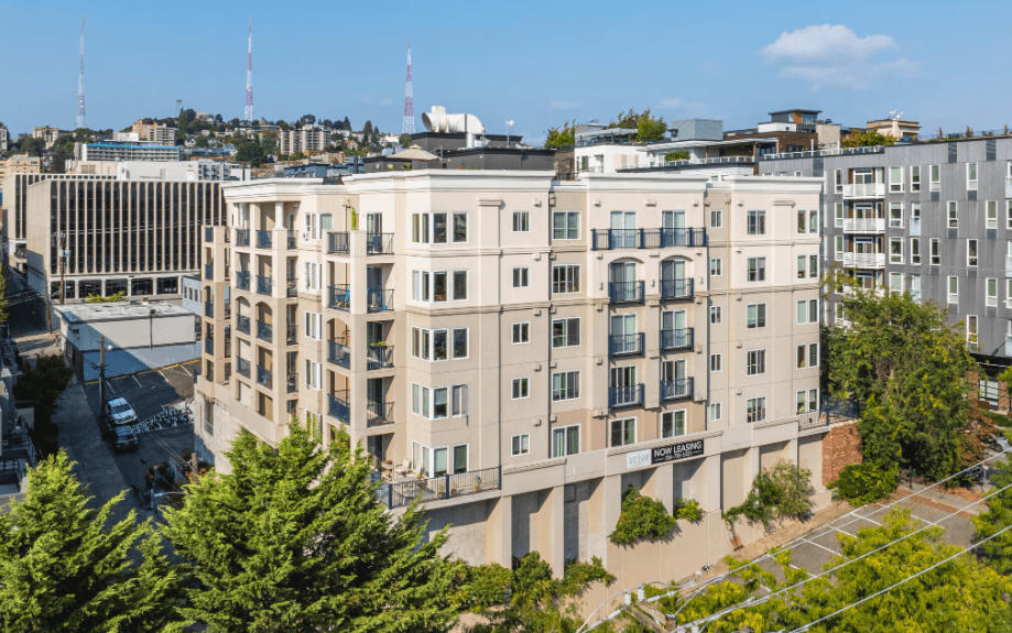 A large beige building with a parking lot in front of it.