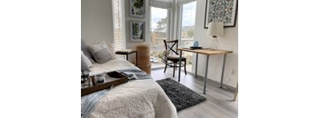 A bedroom with a bed, chair, and table.