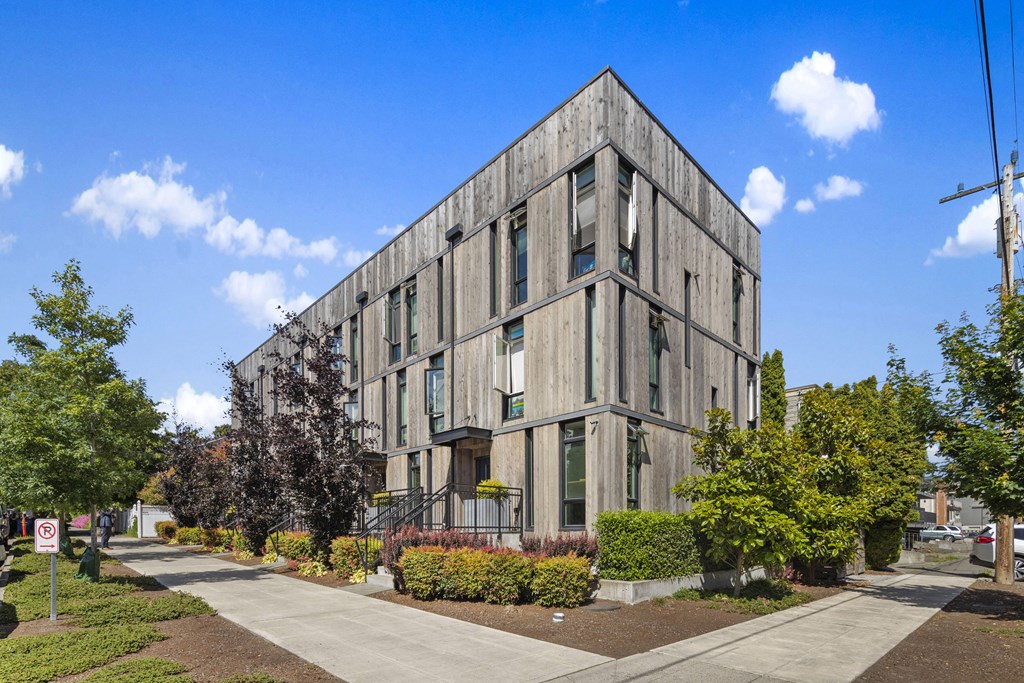 a gray building with a sidewalk and trees in front of it