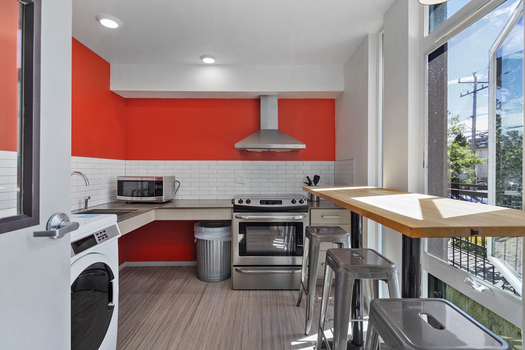 a kitchen with an orange accent wall and stainless steel appliances