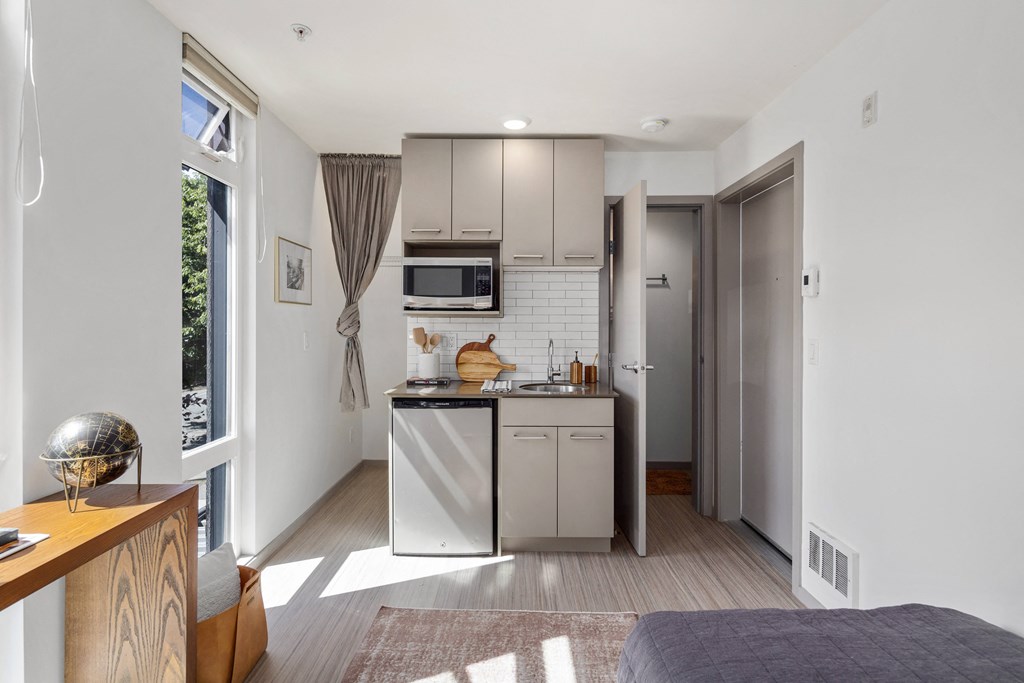 a small kitchen with stainless steel appliances in a studio apartment