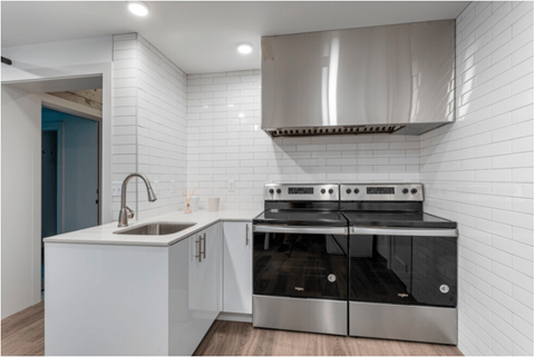 a white kitchen with stainless steel appliances and a sink