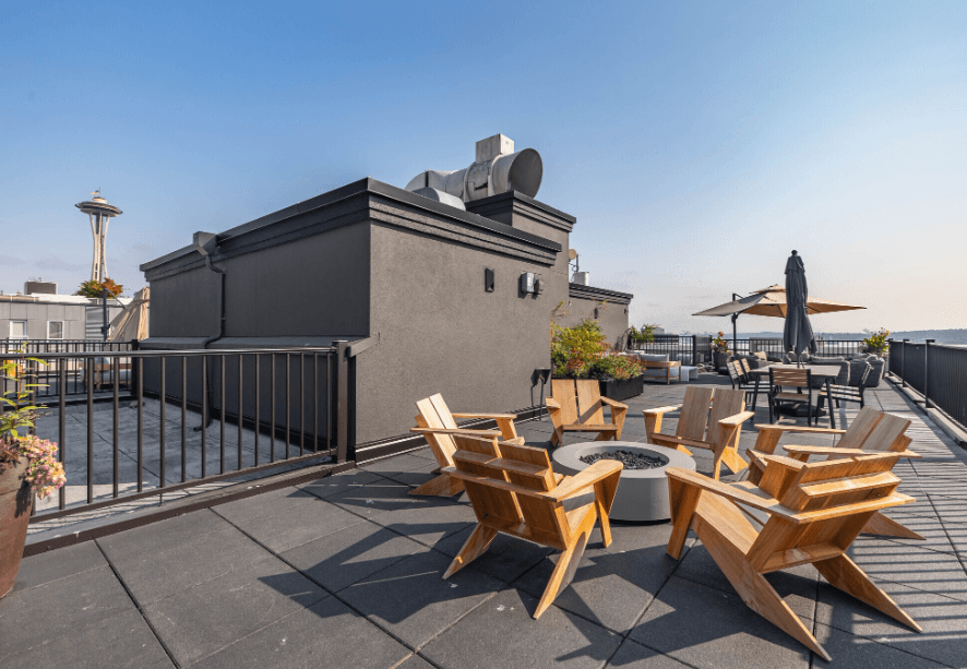A rooftop patio with wooden chairs and a table.