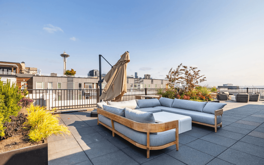 A patio with a couch and a table with a view of the city.