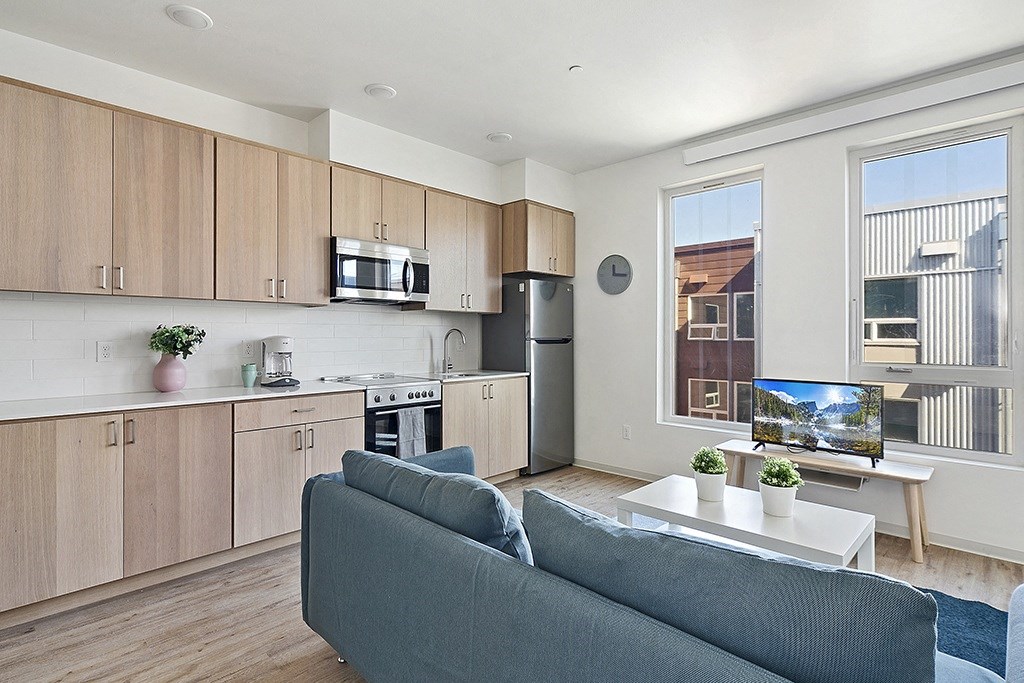 a living room with a couch and a kitchen with wooden cabinets