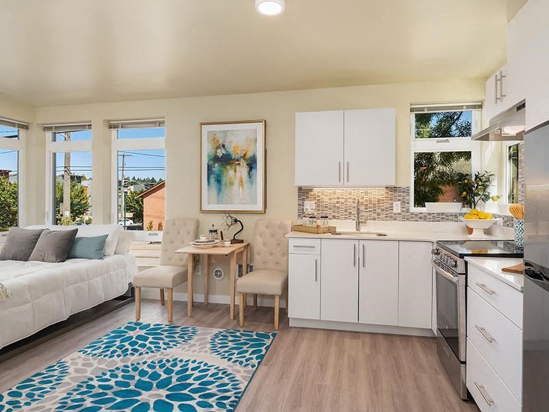a living room with a kitchen and a rug